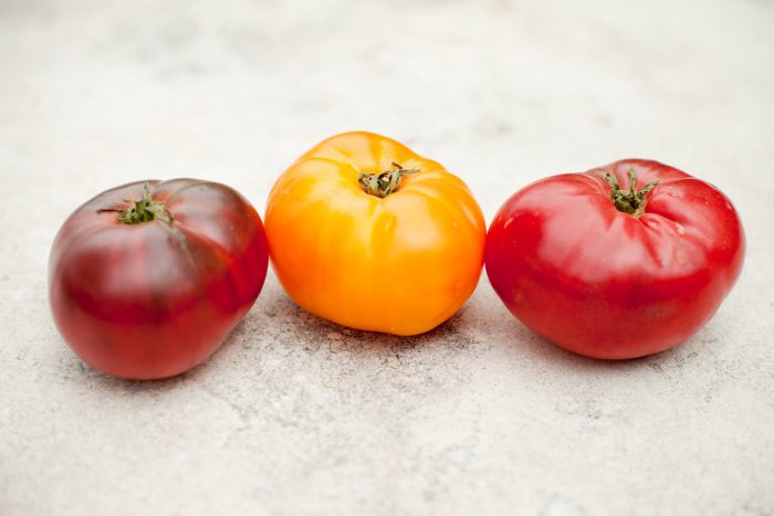 Three tomatoes on a marble surface to be used in Pasta with Tomatoes and Lemon