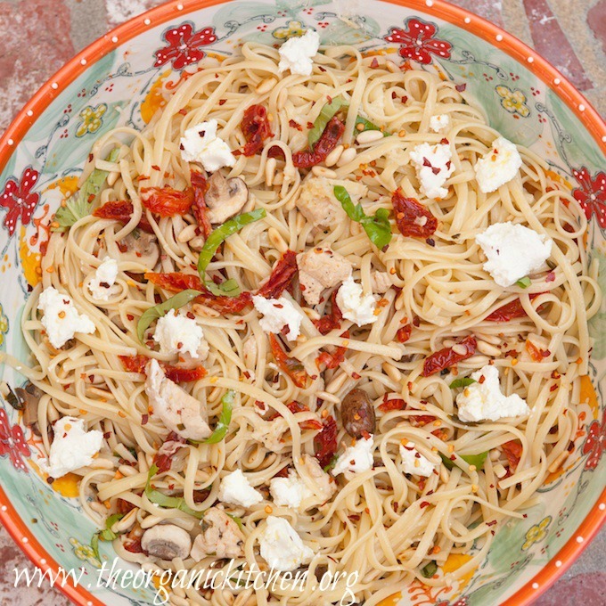 A brightly colored bowl filled Linguini with Chicken and Goat Cheese and garnished with basil
