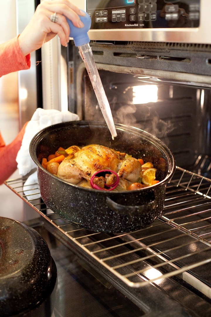 An open oven with a female's hand basting Roasted Apricot Chicken 