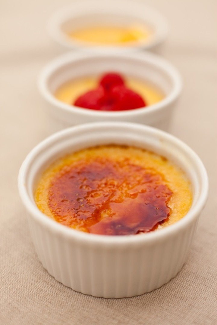 Three ramekins of Orange Vanilla Creme Brûlée set on beige table cloth