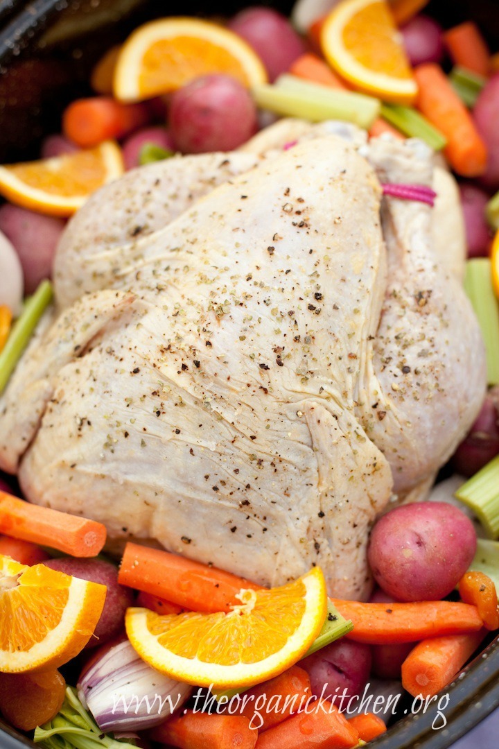 A large whole chicken before roasting, surrounded by raw potatoes, carrots and celery prepped to make Roasted Apricot Chicken