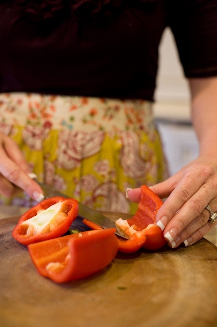 A females hands cutting a red bell pepper on a cutting board