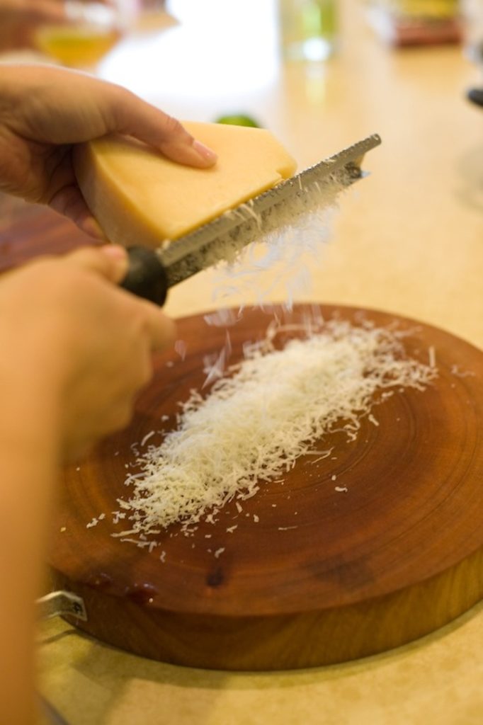 A woman's hands grating parmesan cheese