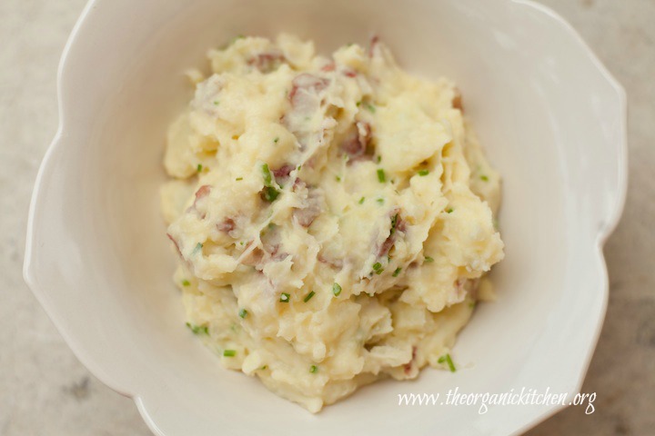 A small white bowl filled with decadent smashed potatoes