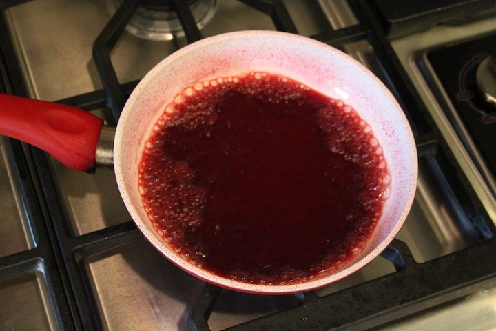 A pan on a cooktop with pomegranate juice in it 