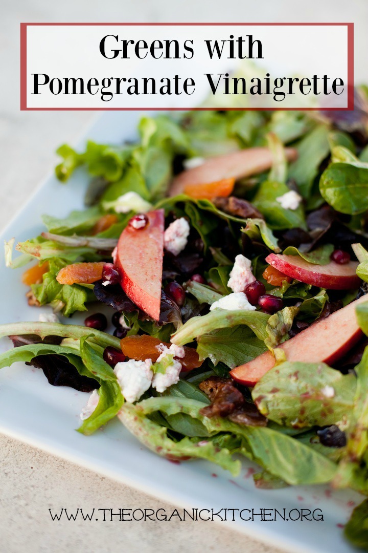 Greens with Pomegranate Vinaigrette on a white platter set on a marble surface