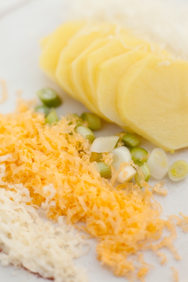 The ingredients for Three Cheese Au Gratin Potatoes: potato slices, green onions, shredded cheddar , parmesan and colby jack