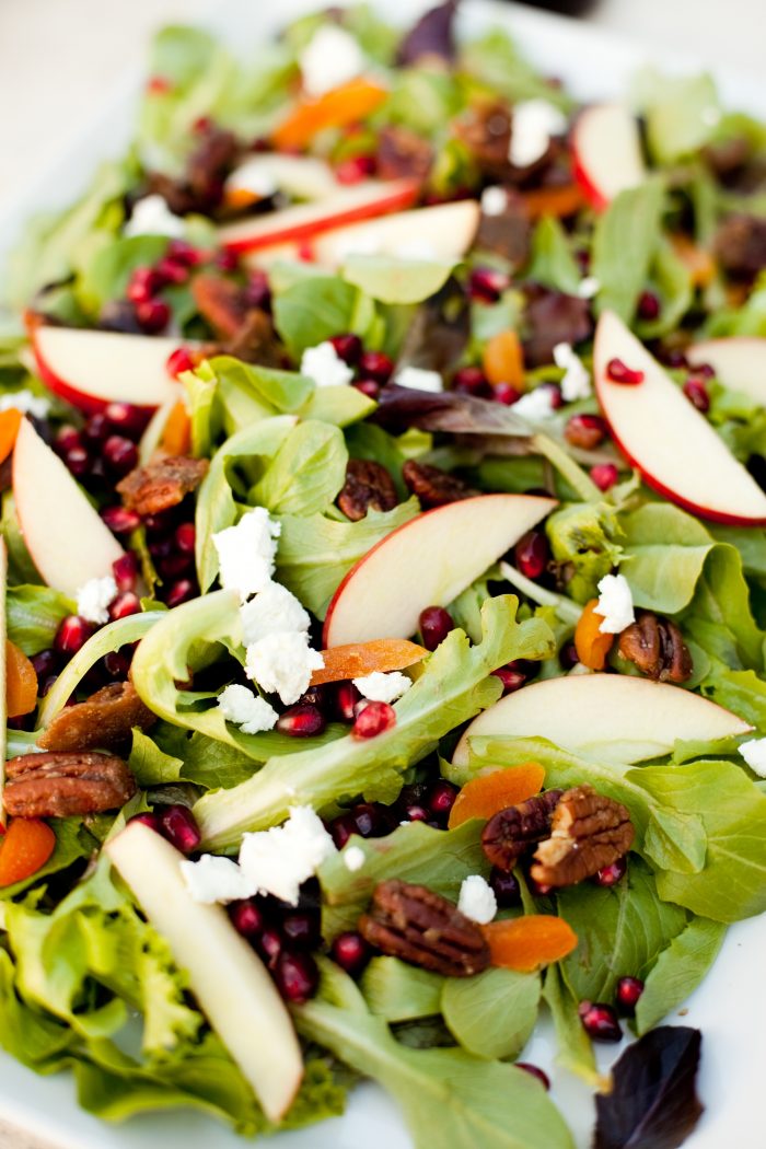 Greens with Pomegranate Vinaigrette on white platter before being dressed