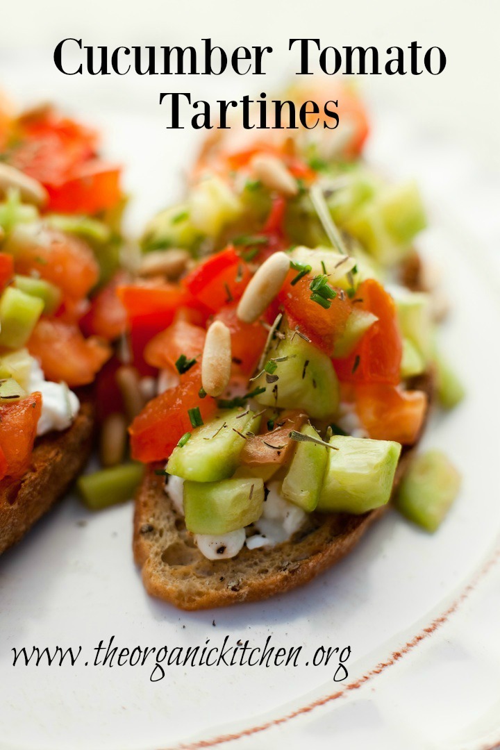 Two Cucumber Tomato Tartines garnished with pine nuts on a white plate