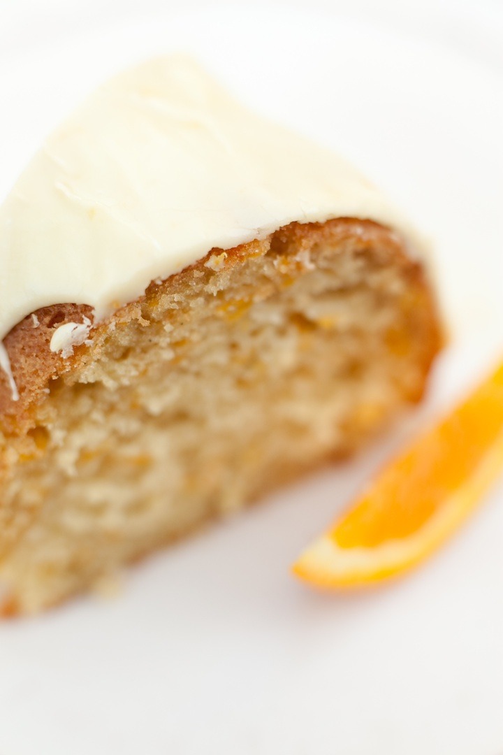 A slice of The Best Lemon Cake Ever on a white plate with orange slice