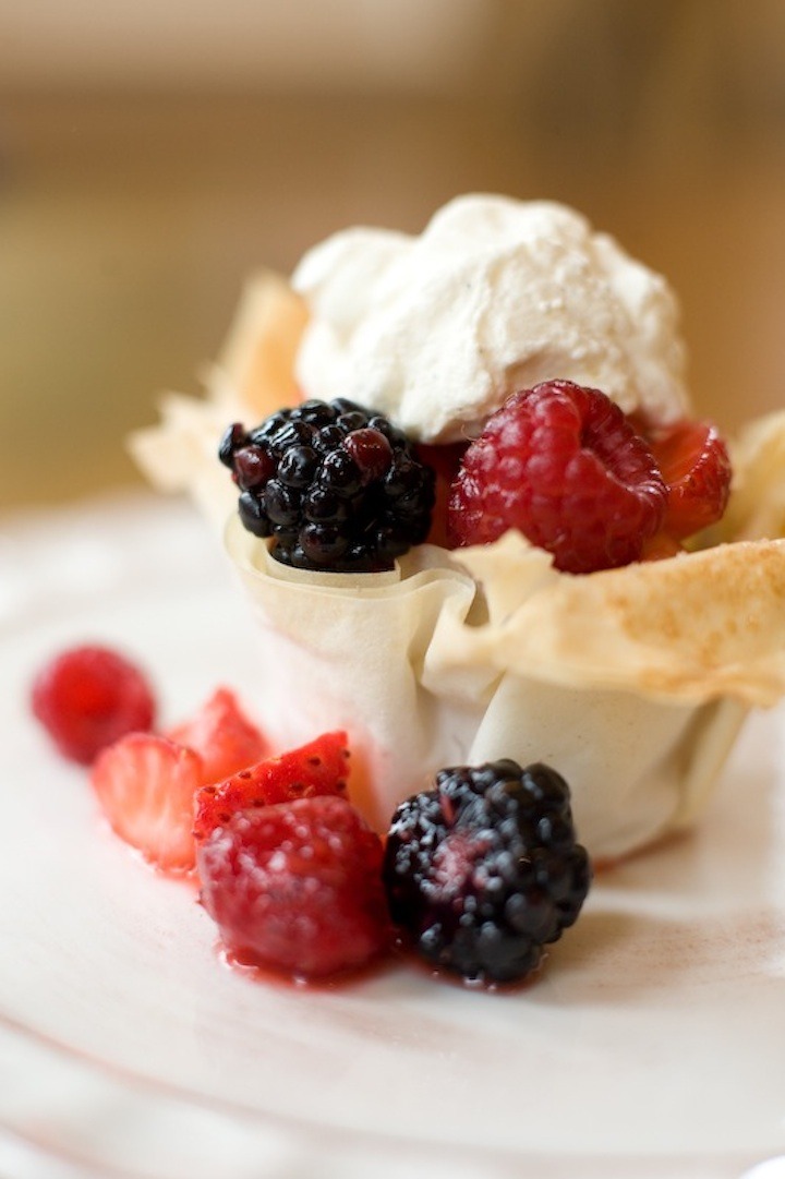 Berries in a Pastry Basket topped with whipped cream on white plate 