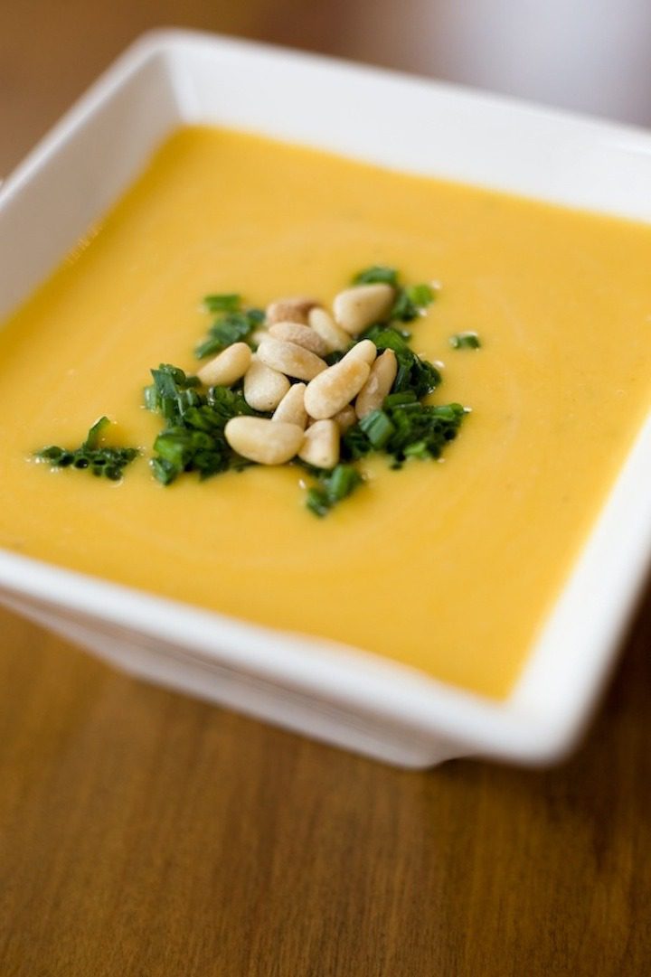A square white bowl of Easy Butternut Squash Soup on a brown wood table
