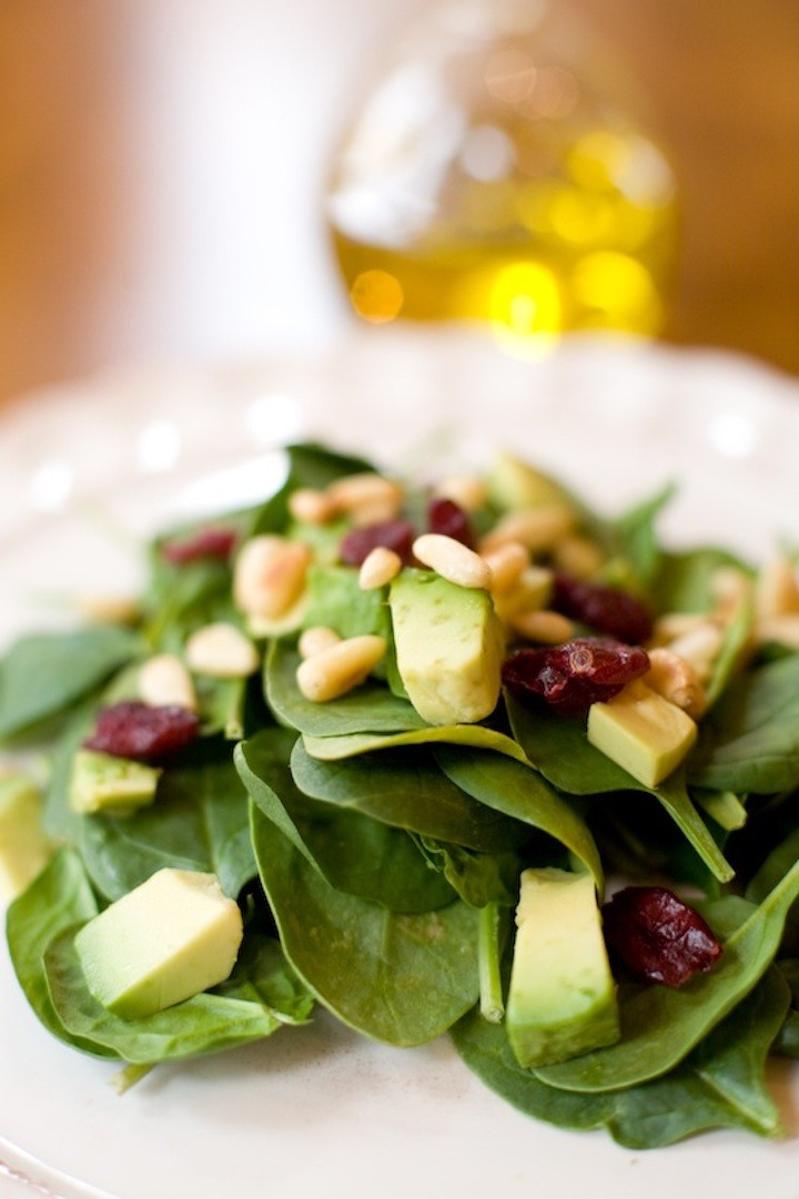 spinach salad with white balsamic on a white plate with a small bottle of salad dressing in the background