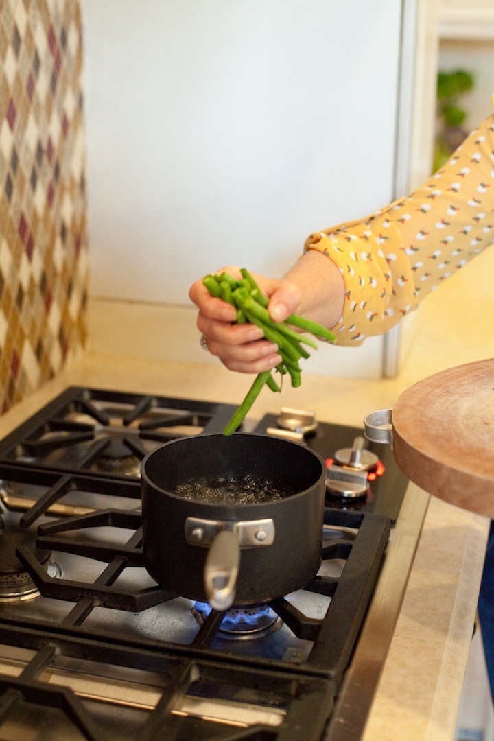 I females right hand dropping green beans into a pot of boiling water, to demonstrate how to make simple blanched green beans