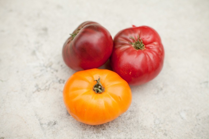 Three heirloom tomatoes on marble surfdace