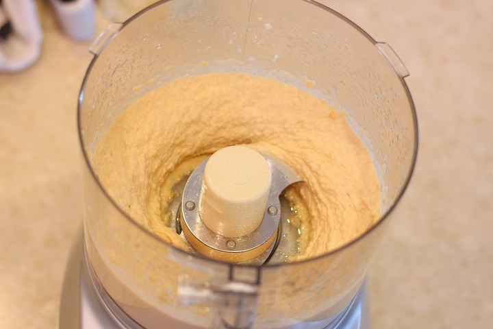 a food processor bowl filled with freshly made hummus