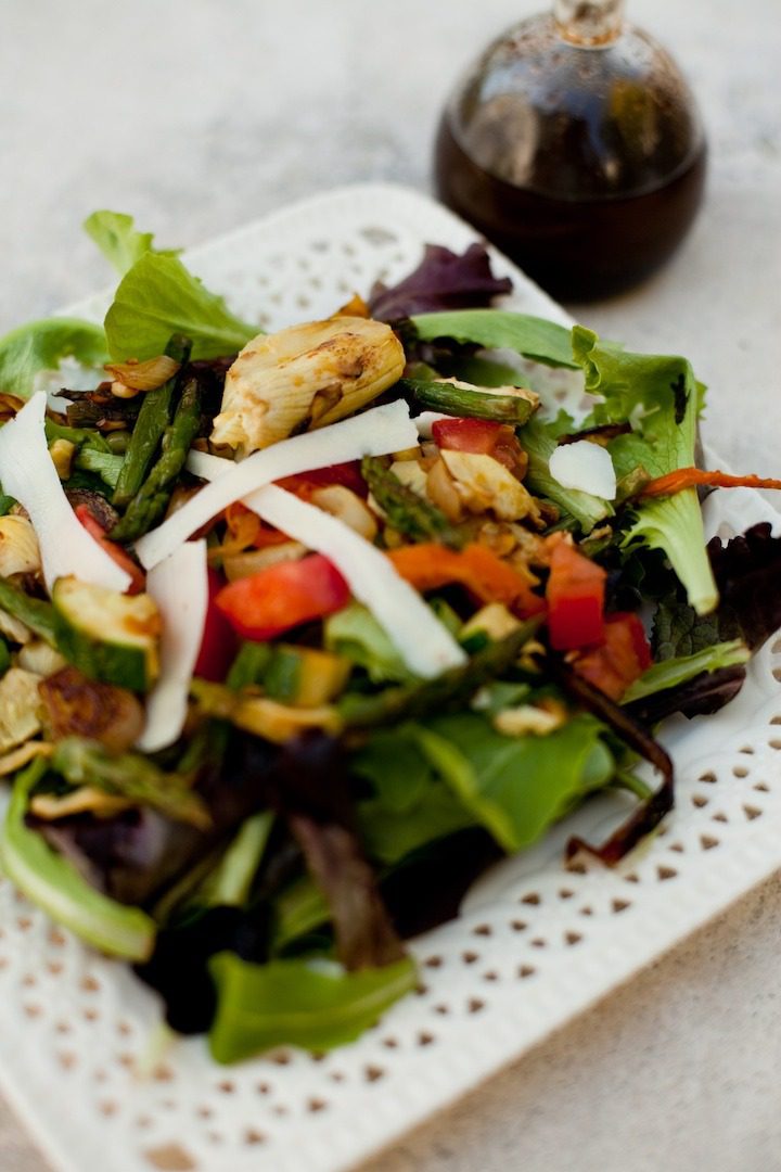 25 Summer Salad Recipes A Grilled Vegetable Salad on a white plate with bottle of balsamic vinaigrette in the background