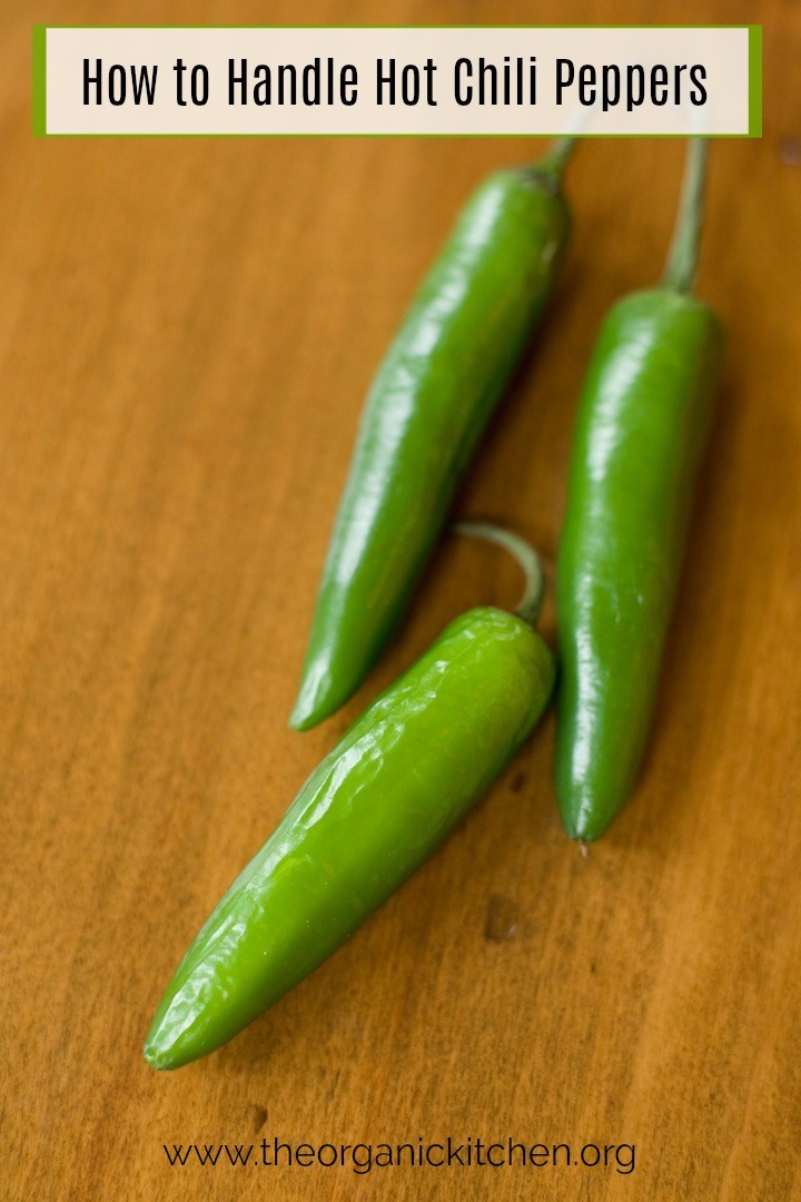 How to Handle a Hot Chili Pepper! Three green serrano chilis on a brown table