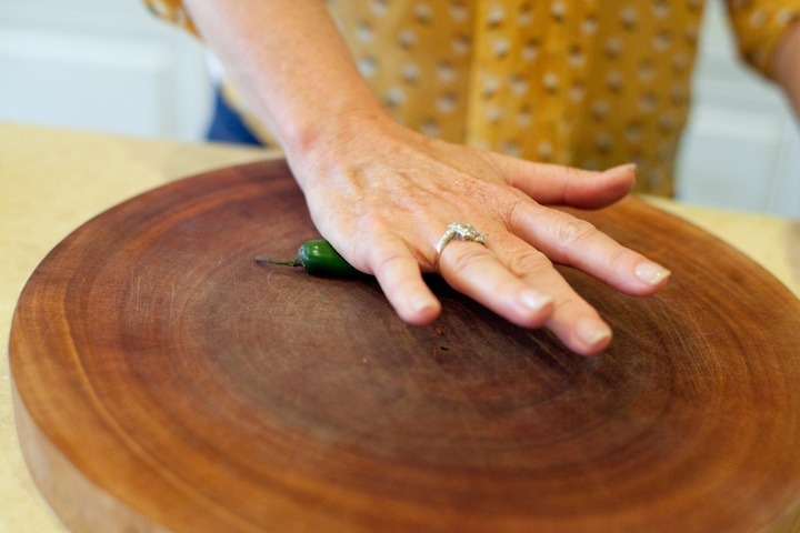 How to Handle a Hot Chili Pepper: a woman's hand rolling a serrano chili on a cutting board