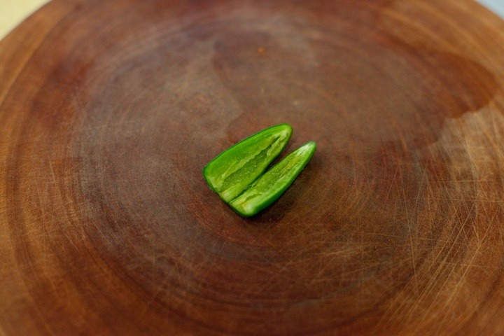 How to Handle a Hot Chili Pepper: a serrano chili cut in half on a cutting board, seeds and pith removed