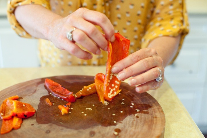 A female's hands holding a slice of red bell as part of a domonstration on How to Roast a Red Bell Pepper