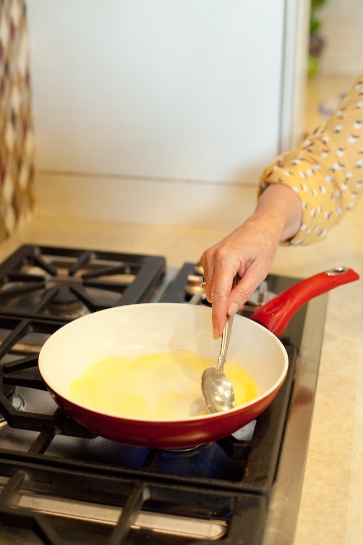 A females hand holding a spoon and melting butter in a pan to be used in a demonstration of How to Caramelize Nuts!
