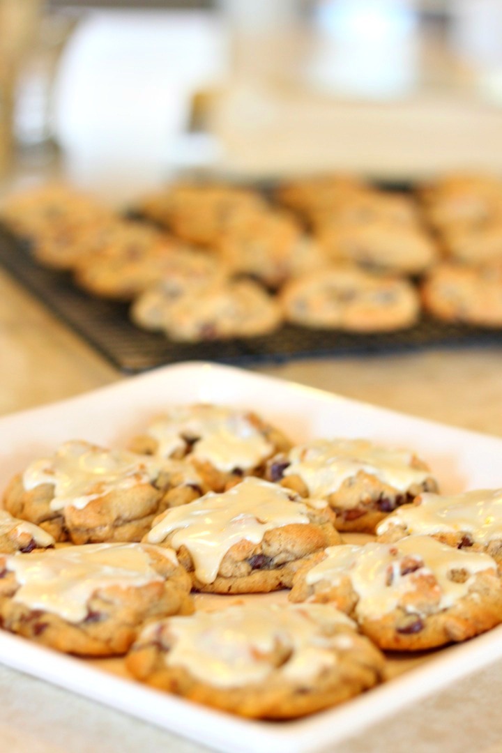 Chocolate Chip Oatmeal Cookies with Orange Glaze on a white plate in the foreground and on a cooling rack in the background