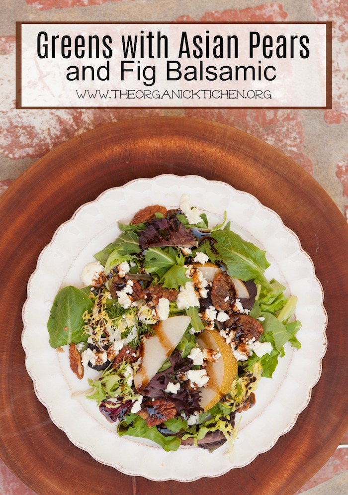 "Greens with Asian Pears and Fig/Maple Balsamic Vinaigrette" on a white plate with scalloped edges set on a wooden cutting board