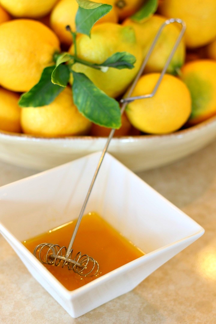 a bowl full of lemons next to another bowl of salad dressing