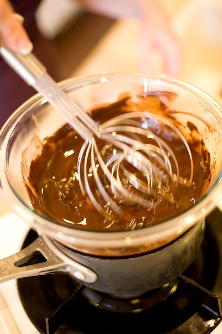 A woman's hand whisking melted chocolate in a double boiler. How to Make Chocolate Bark