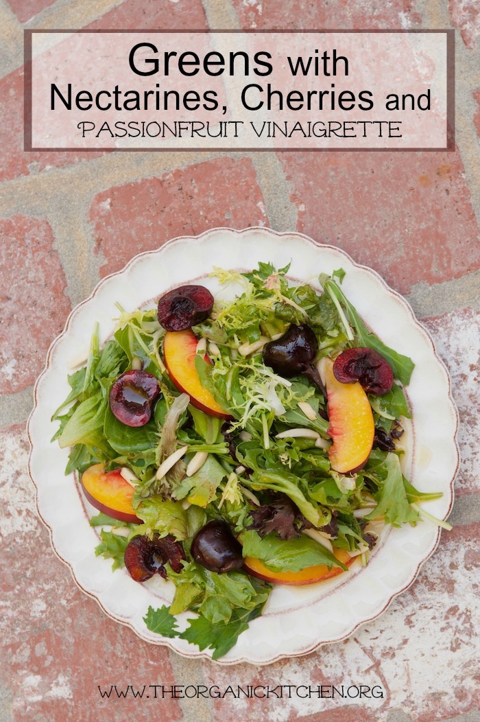 Greens with Cherries, Nectarines and Passionfruit Vinaigrette on white plate with scalloped edges set on brick backdrop