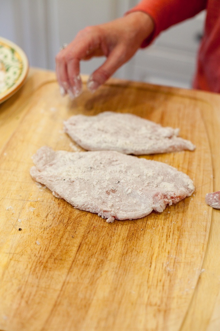 A woman showing how to dredge chicken breasts in flour for use in Chicken Piccata from The Organic Kitchen