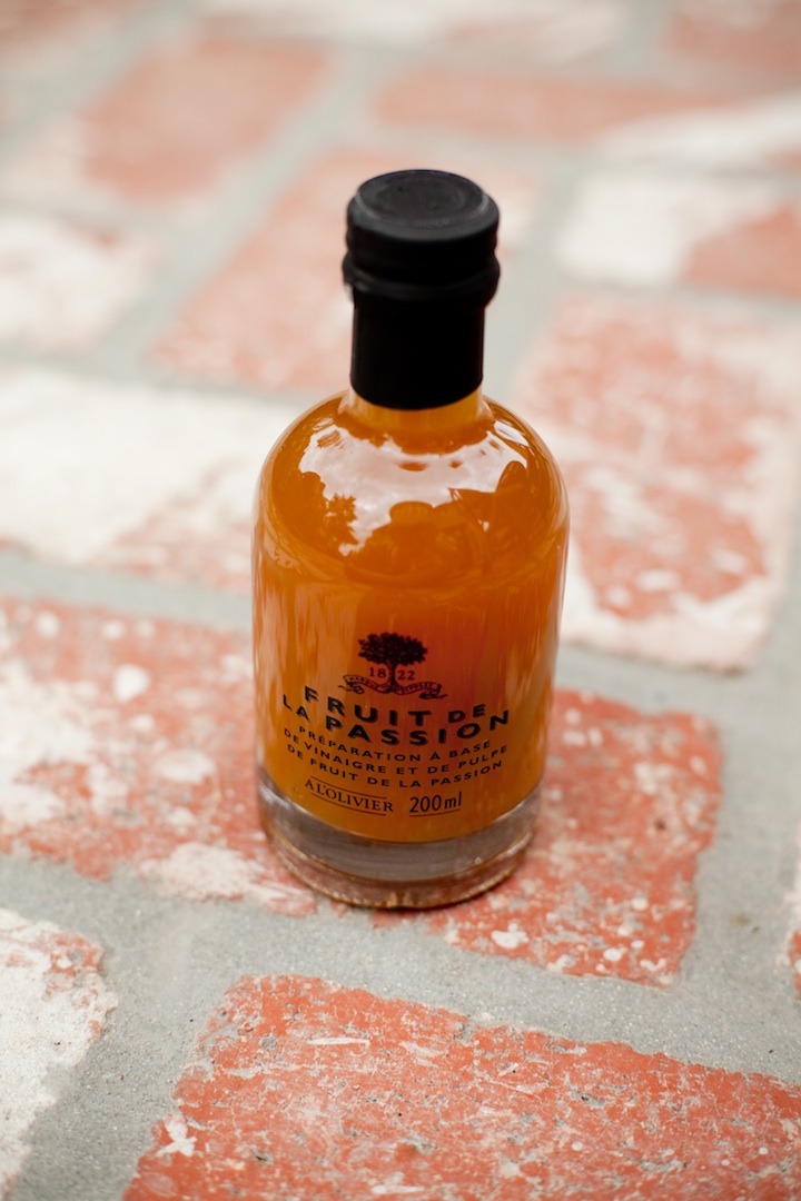 A bottle of passionfruit vinegar on brick surface. Greens with Nectarines and Cherries