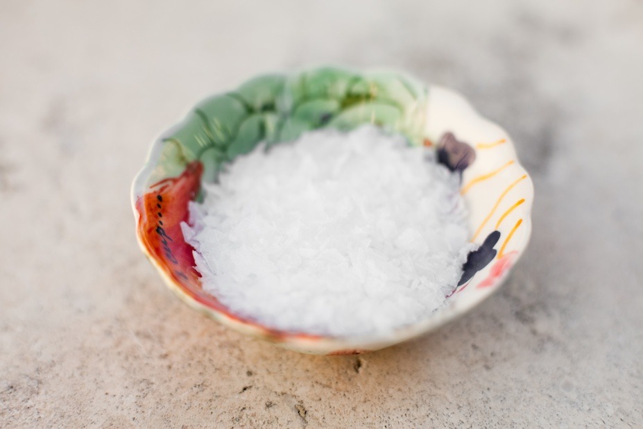 A small colorful bowl of sea salt on a marble surface