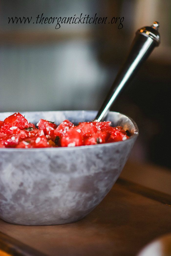 Watermelon salad with mint and feta in a greay bowl with silver serving spoon