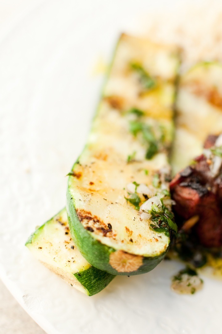 Simple Grilled Zucchini garnished with chimichurri on white plate 