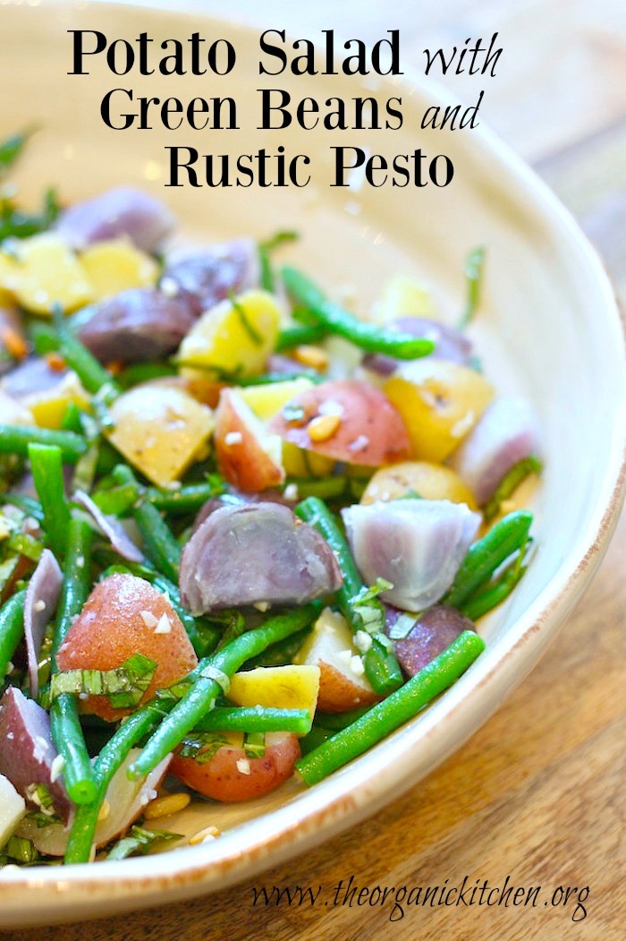 Tri-colored Potato Salad with Green Beans and Rustic Pesto in a large grey bowl set on a wooden table