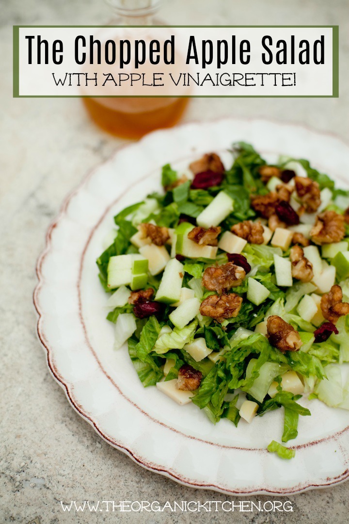 The Organic Kitchen Chopped Salad with Apple Vinaigrette served on a white plate with a bottle of salad dressing in the background