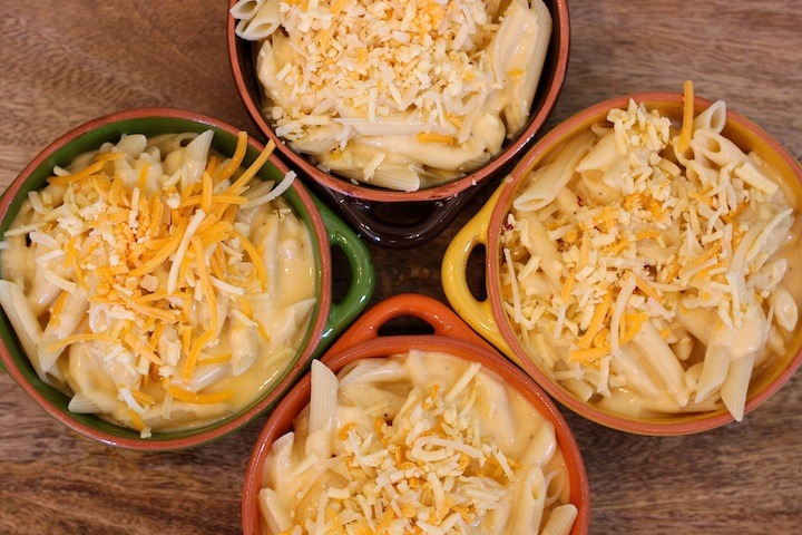 Spicy Penne Rigate in colorful baking dishes on wood surface