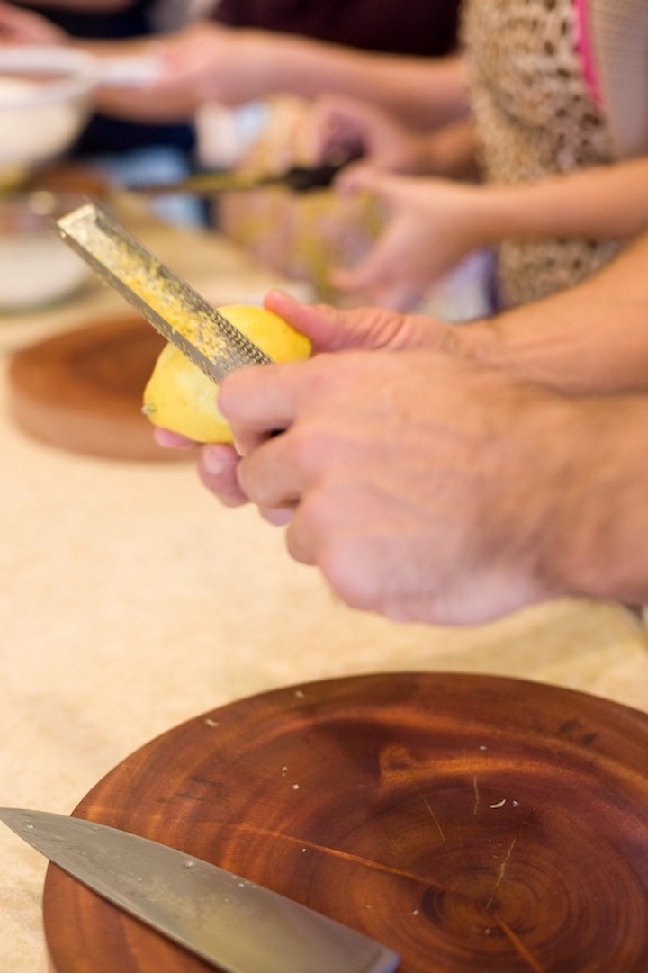 A man's hands demonstrating how to use a microplane to remove the zest of a lemon for Pasta Salad with Greens and Asparagus