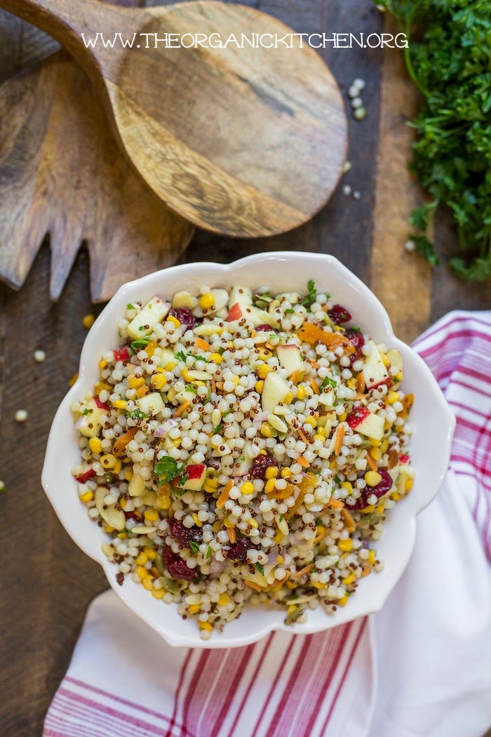 Couscous and Apple Salad in a flower shaped white bowl on wood surface with wood serving utensils