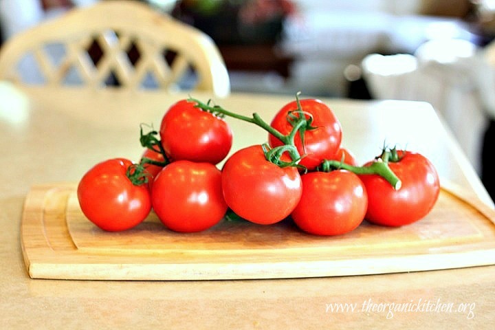 A bunch of organic tomatoes on a cutting board: Creamy Carrot Tomato Soup: Comfort Food at it's Finest