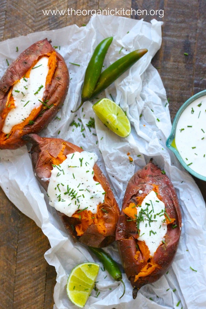 Baked Sweet Potatoes with Spicy Maple Creme Fraiche on crumpled parchment with lime wedges and serrano chilis