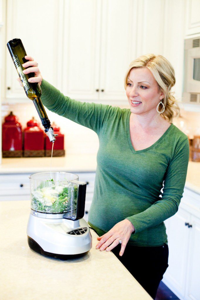 Tortellini with Fresh Basil Pesto A blond woman pouring olive oil into a food processor to make Tortellini with Fresh Basil Pesto