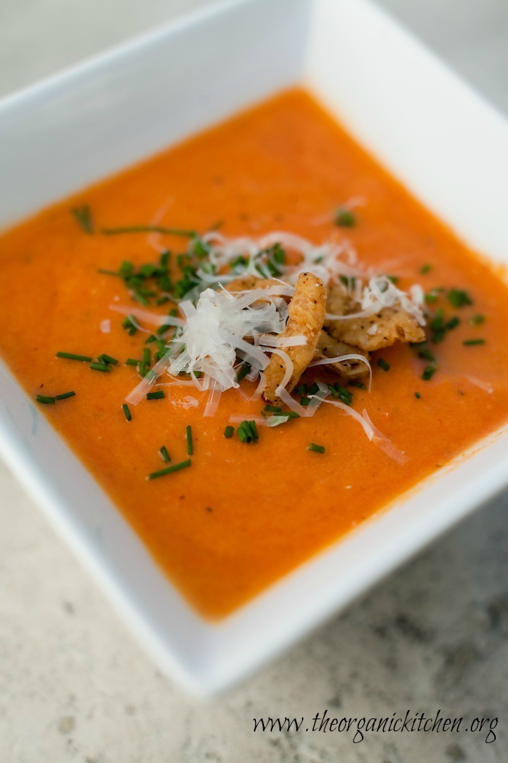 A white bowl full of Creamy Carrot Tomato Soup set on marble surface