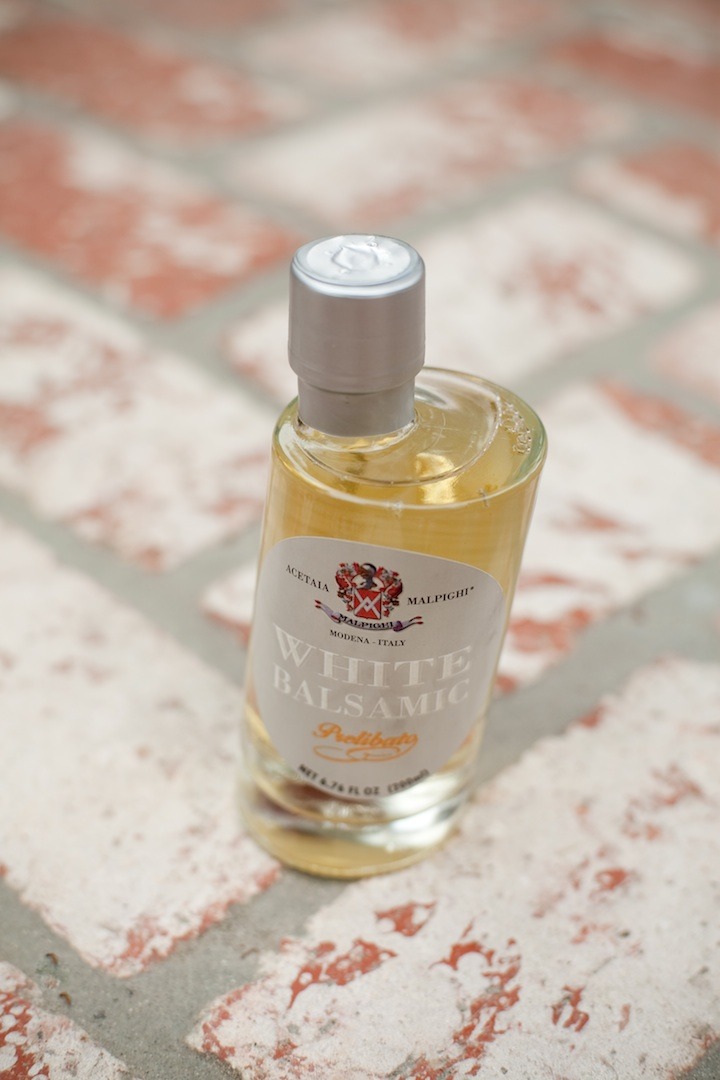 A bottle of white balsamic vinegar on a brick surface