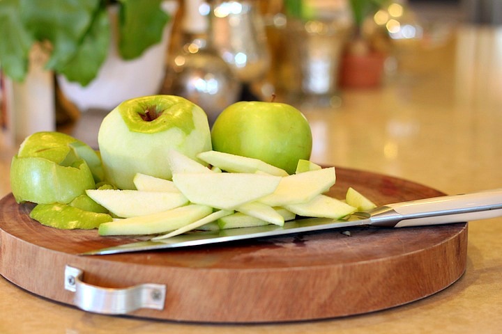 Sliced granny Smith apples and knife on a cutting board