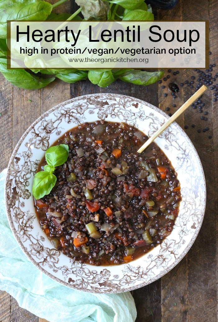 Hearty Lentil Soup on a brown and white bowl with gold spoon garnished with basil