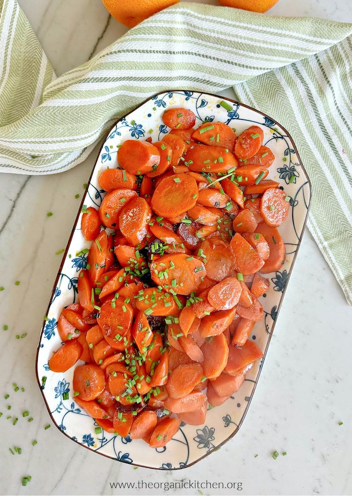 Sautéed Carrots Three Ways: Simple or Dressed for The Holidays on blue and white plate with green dishtowel above