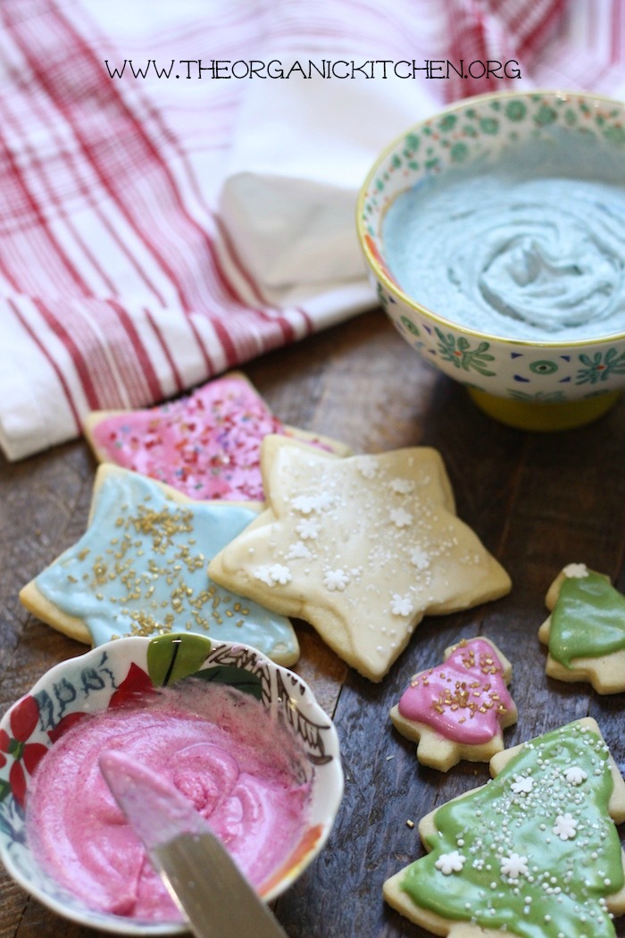 Traditional Rolled Sugar Cookies with a New Twist on wooden table with bowls of pink and blue icing